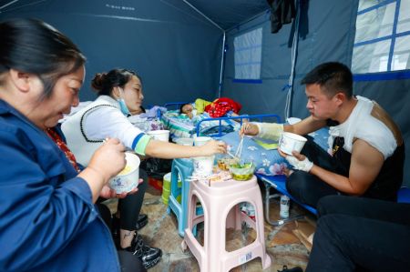 (miniature) Des personnes prennent un repas dans un abri d'urgence après le séisme dans le bourg de Moxi du district de Luding