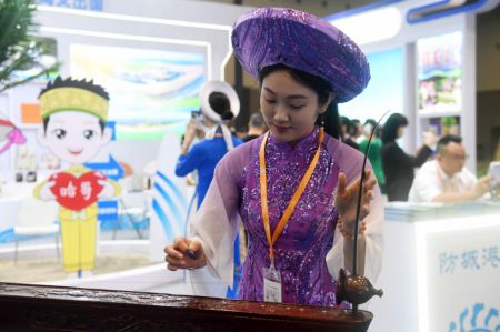 (miniature) Une femme joue d'un instrument folklorique à corde unique lors de l'exposition du tourisme de l'Expo Chine-ASEAN 2023 à Guilin