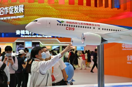 (miniature) Des gens devant un modèle réduit de l'avion C919 lors de l'exposition sur les réalisations du commerce des services de la Chine