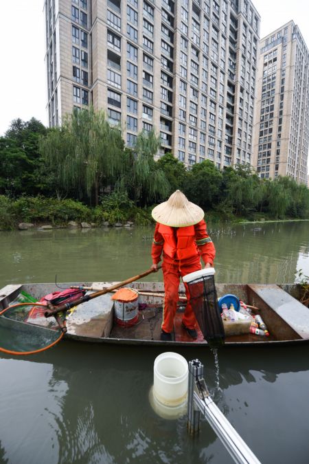 (miniature) Un travailleur sanitaire collecte des déchets recueillis par une machine sur une rivière à Hangzhou