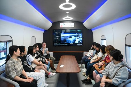 (miniature) Des étudiants américains participant à une tournée éducative en Chine se renseignent sur une ligne d'essai pour un prototype de locomotive utilisant la technologie maglev supraconductrice à haute température à Chengdu