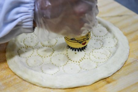 (miniature) Un ouvrier crée des motifs sur des pains locaux plats (Nang) dans un atelier d'un parc industriel à Horgos