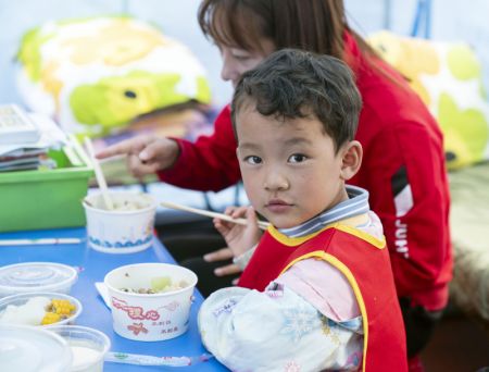 (miniature) Un enfant prend son repas dans un abri de secours à la suite du séisme