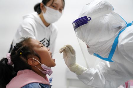 (miniature) Une fille reçoit un test d'acide nucléique dans un point de tests de l'arrondissement de Nangang à Harbin