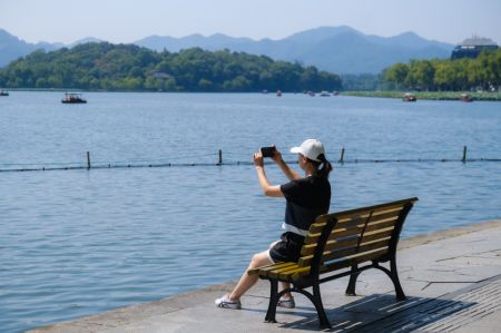 (miniature) Une touriste prend des photos de la zone touristique du lac de l'Ouest pendant les congés de la fête nationale