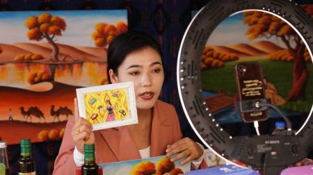 (miniature) Une présentatrice montre une peinture lors d'un programme de live streaming dans le bourg de Kumkusar du district de Makit