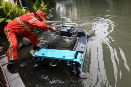 (miniature) Un travailleur sanitaire collecte des déchets recueillis par un bateau de patrouille autonome sur une rivière à Hangzhou