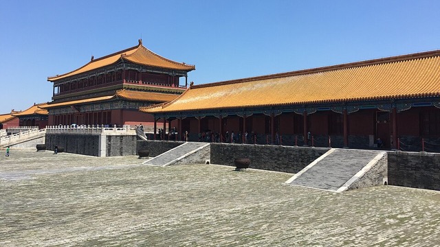 Le belvédère de la Bienveillance incarnée et la longue galerie basse qui le prolonge, vus en oblique par-dessus les rampes de pierre de la grande terrasse, sous un ciel bleu.