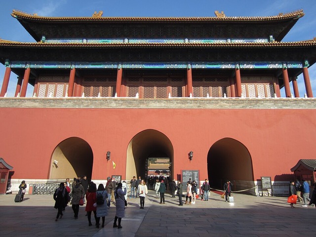 La face sud de la porte de la Prouesse divine : trois passages voûtés percés dans le massif rouge, sous le pavillon à colonnes rouges et double toit.