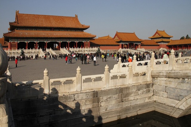 La porte de l’Harmonie suprême et les deux portes latérales vues depuis l’un des ponts de marbre, dont la balustrade sculptée occupe le premier plan, avec des visiteurs dans la cour.