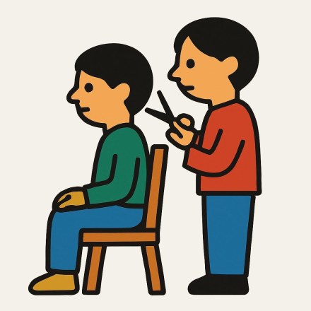 A person in a green top sitting sideways on a wooden chair while another in a red top, standing behind, brings scissors up to their hair.