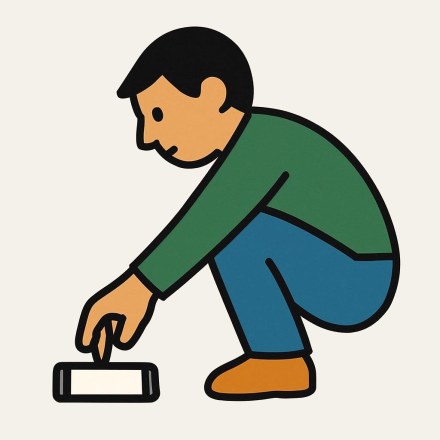 Picture 2 — A man crouching, seen from the side, in a green top and blue trousers, his arm stretched down and his hand closed on a small phone with a pale screen.