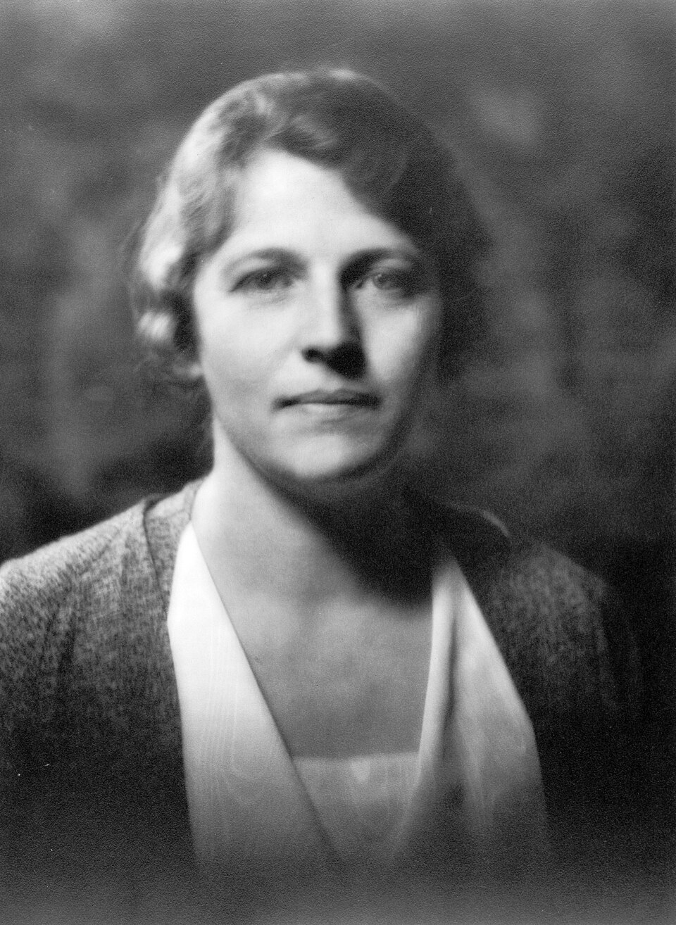 Portrait photographique en noir et blanc d’une femme aux cheveux ondulés ramenés en arrière, de trois quarts, le regard tourné de côté