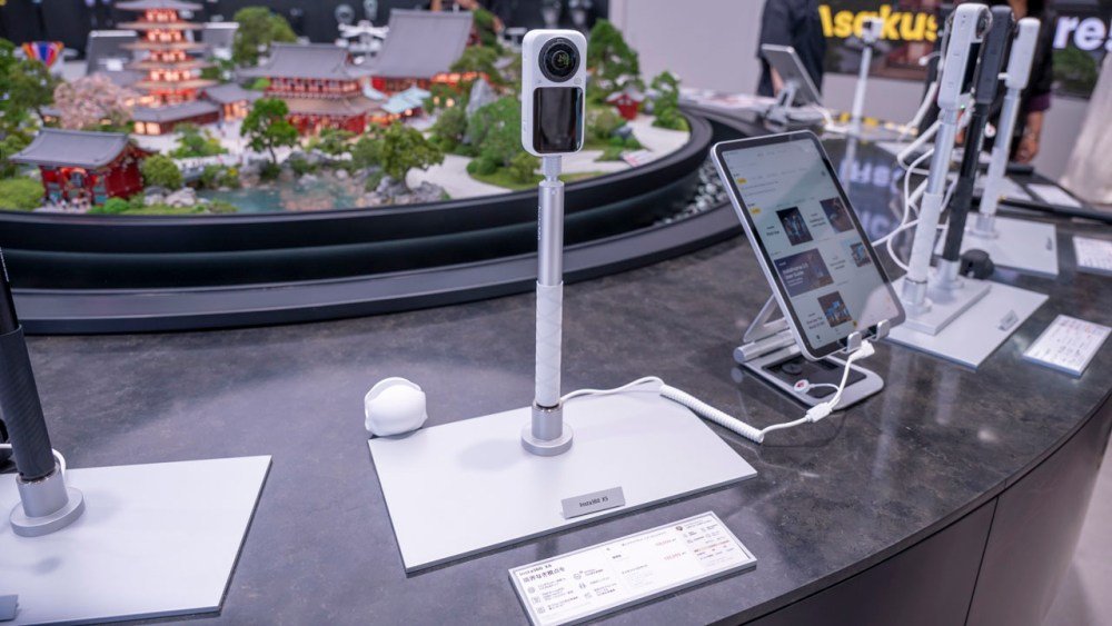 Des caméras Insta360 exposées sur un comptoir du magasin, devant une maquette miniature d'un temple