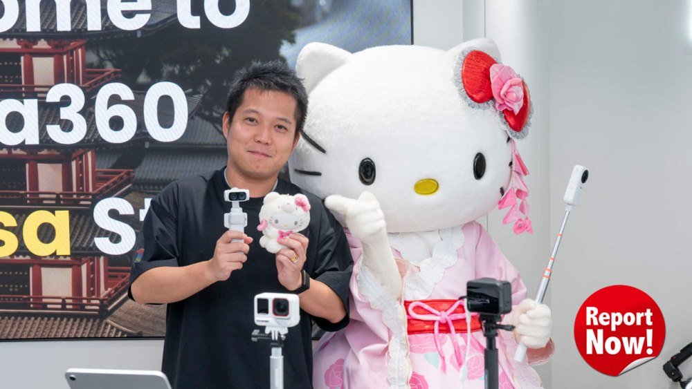 Un homme tient une caméra Insta360 et une peluche Hello Kitty aux côtés de la mascotte Hello Kitty grandeur nature, lors de l'ouverture du magasin