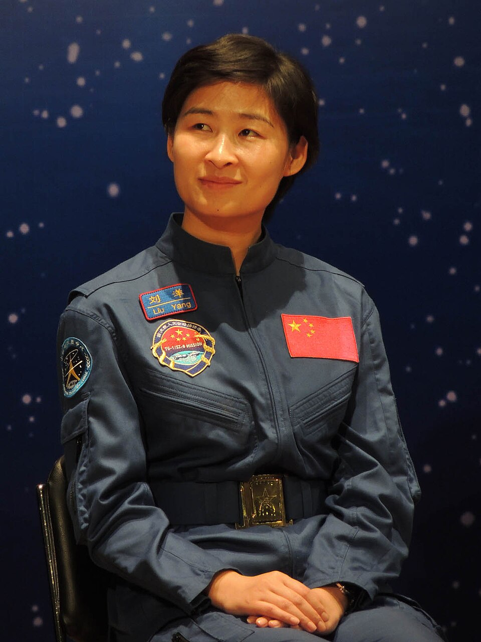 Liu Yang en combinaison de vol bleue, assise devant une toile de fond étoilée