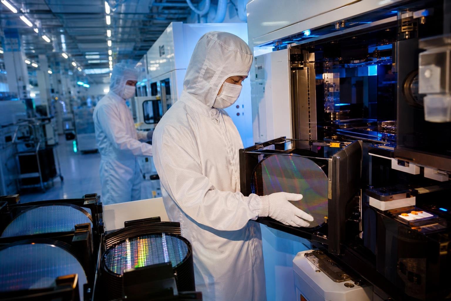 Salle blanche d'une usine de fabrication de puces électroniques, avec des techniciens en combinaison stérile.