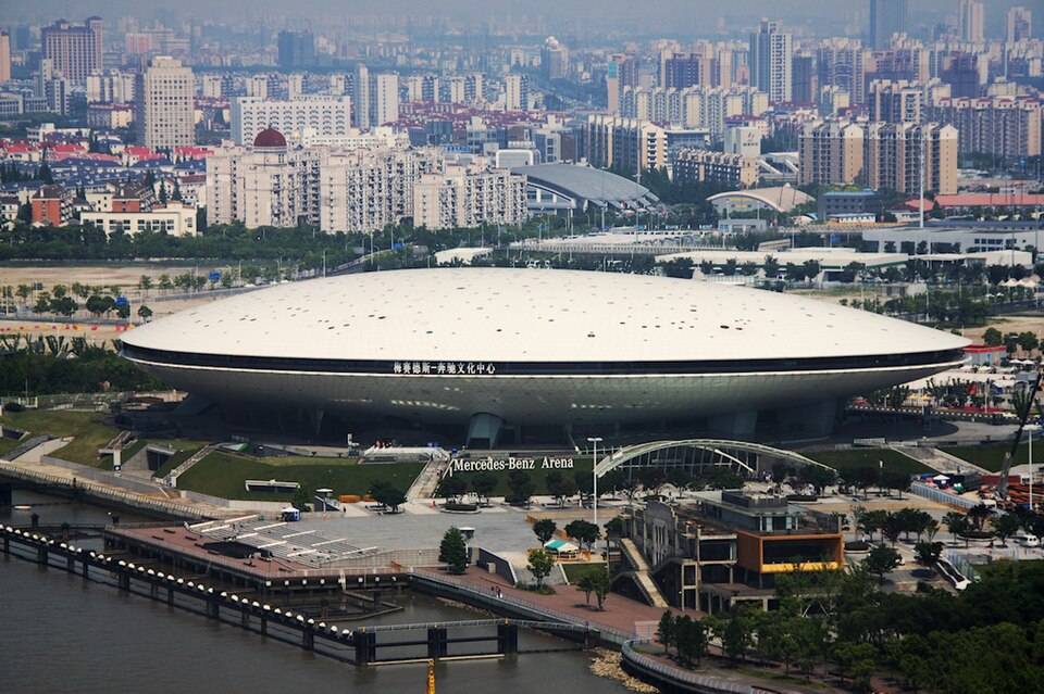 La Mercedes-Benz Arena de Shanghai, salle blanche en forme de soucoupe au bord du fleuve, dans un quartier d'immeubles.