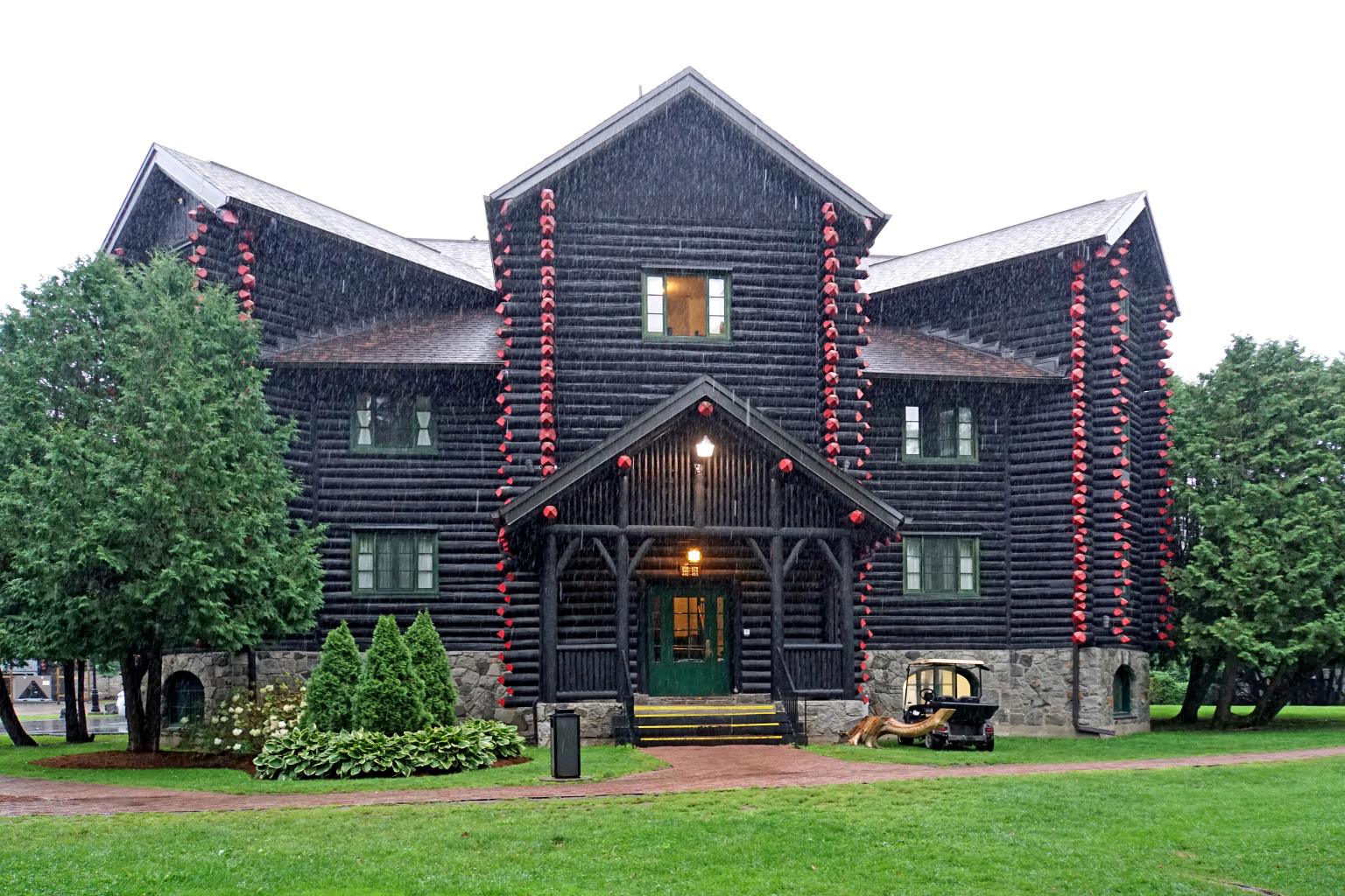 Façade principale du Château Montebello, bâtiment de rondins sombres aux extrémités peintes en rouge