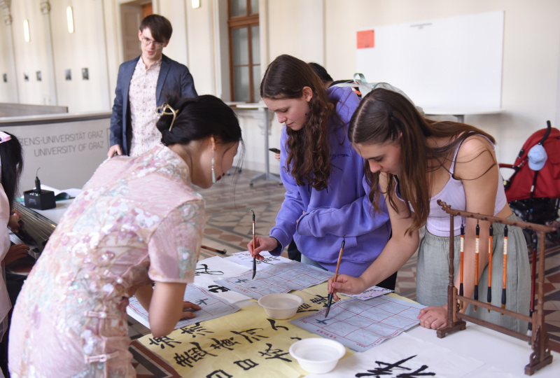 Des personnes pratiquent la calligraphie chinoise lors d'un événement culturel chinois célébrant le traditionnel Festival de la mi-automne à l'Université de Graz