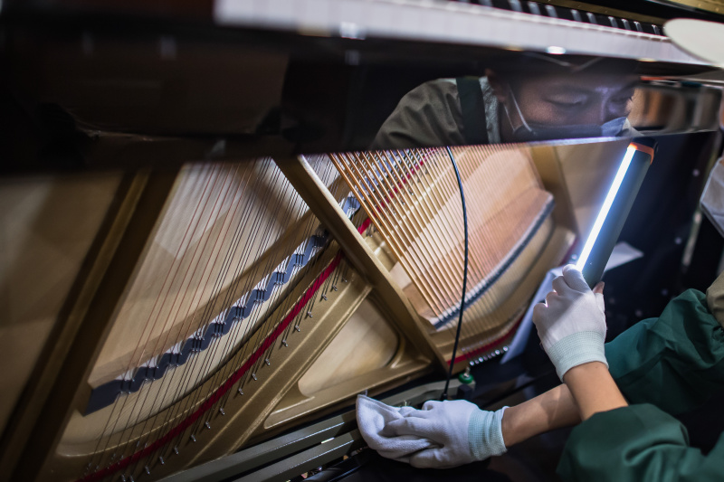 Un ouvrier dans une fabrique de pianos de Parsons Music Corporation
