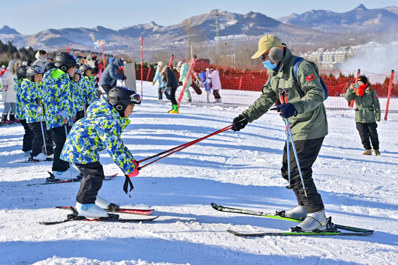 Un moniteur apprend à un enfant à faire du ski dans une station de sports d'hiver à Qingzhou