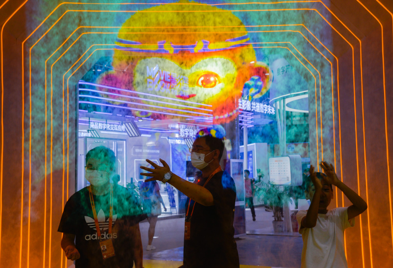 Des visiteurs font l'expérience de la projection holographique dans la zone d'exposition des services de télécommunications