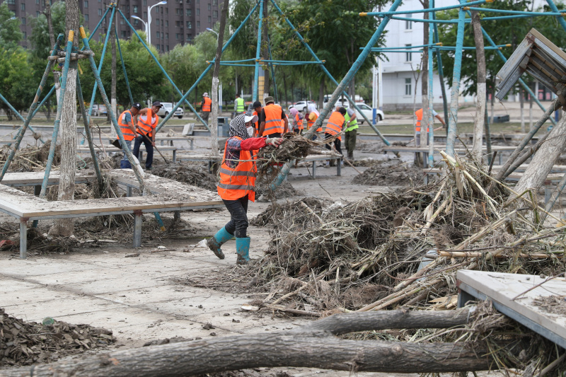 Des travailleurs nettoient une route après les inondations à Shangzhi