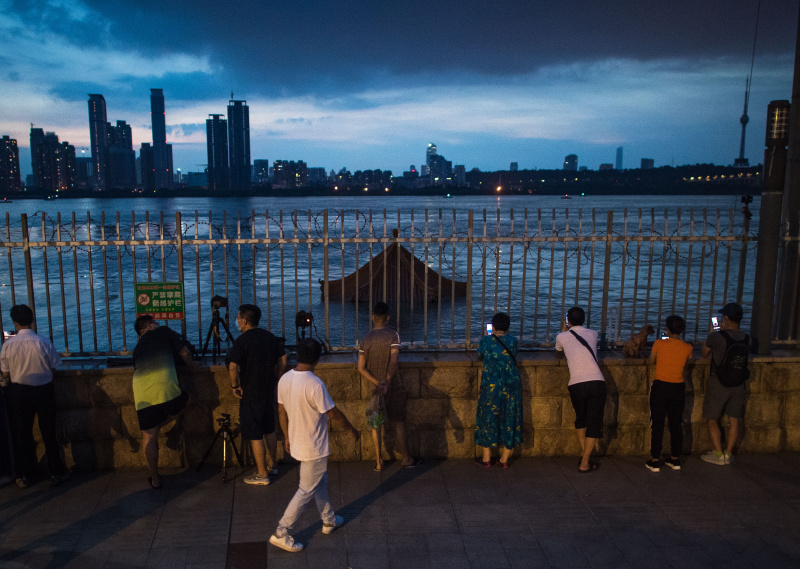 Des gens prennent des photos du fleuve Yangtsé dans lequel un pavillon est submergé par la montée des eaux à Wuhan