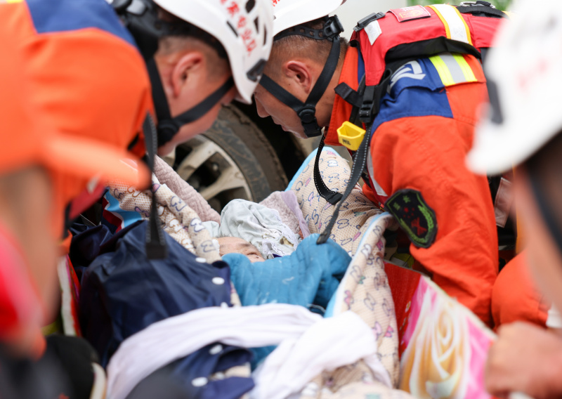 Les sauveteurs transportent un villageois qui s'était retrouvé piégé dans les décombres dans le bourg de Kaiyuan à Shulan