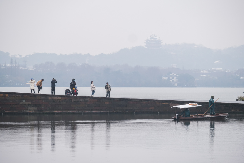 Des touristes contemplent le paysage enneigé de la chaussée de Baidi de la zone pittoresque du lac de l'Ouest à Hangzhou