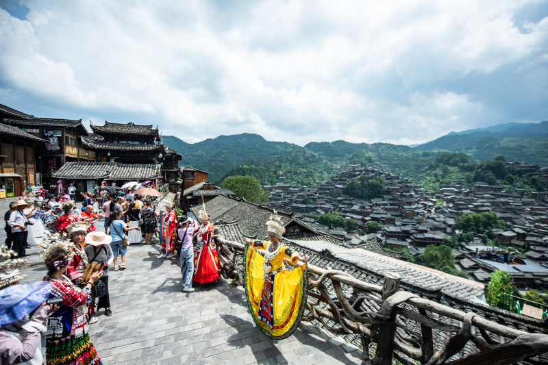 Des touristes posent pour une photo dans le village Miao de Xijiang Qianhu