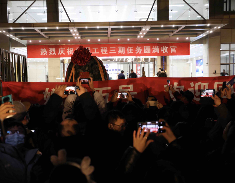 Les gens célèbrent l'arrivée de la capsule de retour de la sonde chinoise Chang'e-5 à l'Académie chinoise de technologie spatiale (ACTS) à Beijing