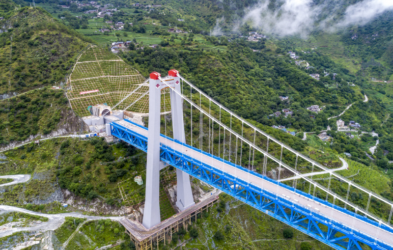 Photo aérienne prise le 26 juillet 2022 montrant le grand pont de la rivière Jinsha au niveau de sa jonction avec l'entrée du tunnel du mont enneigé Haba sur la ligne du chemin de fer Lijiang-Shangri-La dans la province du Yunnan (sud-ouest)