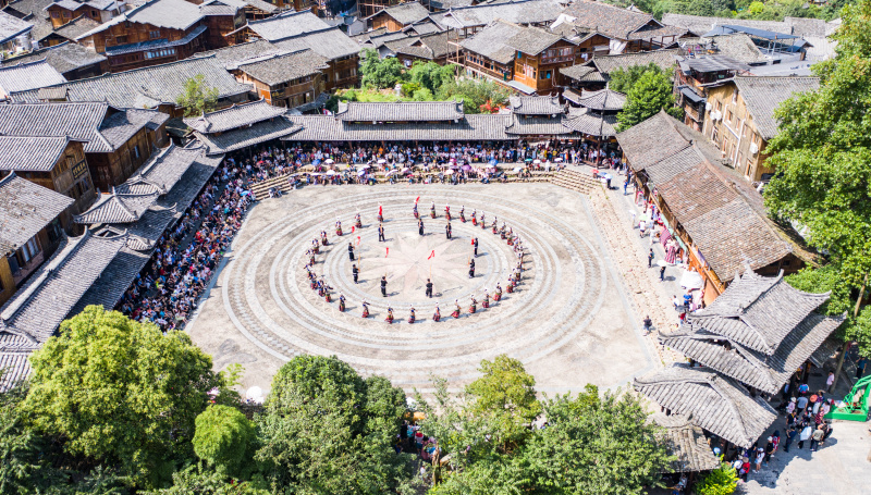 Des touristes regardent un spectacle de danse traditionnelle dans le village Miao de Xijiang Qianhu