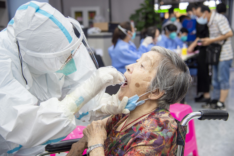 Un professionnel de la santé prélève un échantillon de gorge sur une résidente pour le test d'acide nucléique de la COVID-19 à Wuhan