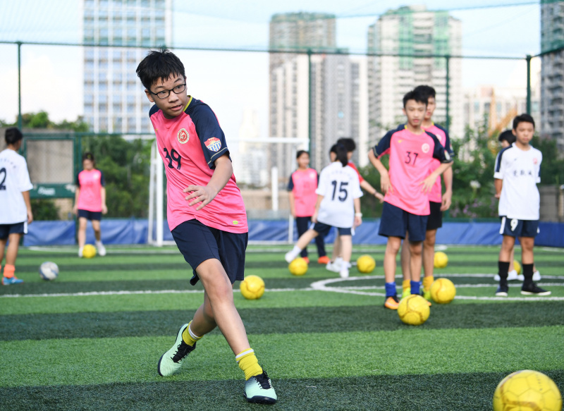 Des enfants participent à une séance d'entraînement sur un terrain de sport aménagé sur le toit d'un bâtiment de l'école secondaire No