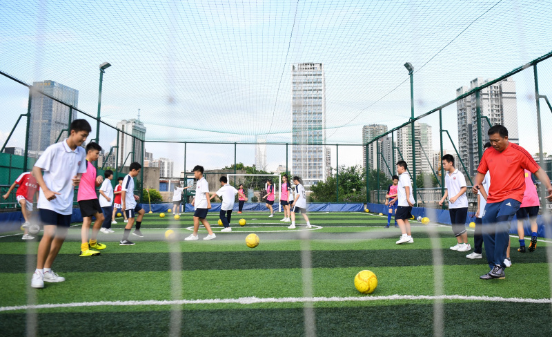 Des enfants participent à une séance d'entraînement sur un terrain de sport aménagé sur le toit d'un bâtiment de l'école secondaire No