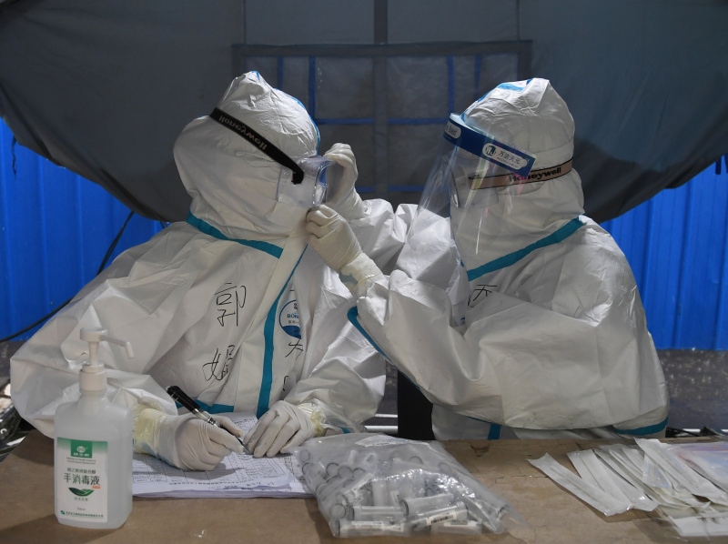 Un professionnel de santé aide son collègue à ajuster ses lunettes de protection dans un site de test d'acide nucléique