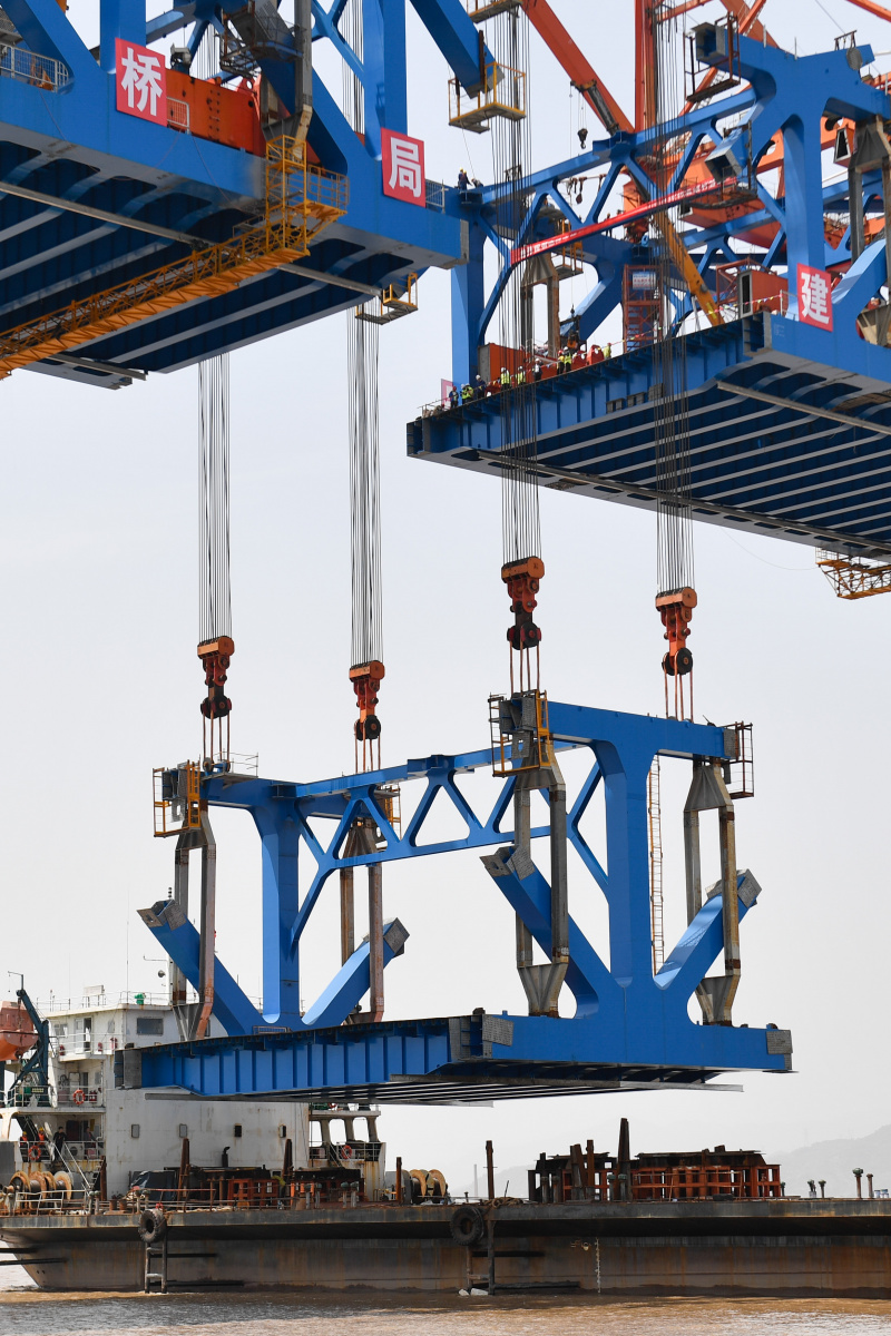 Le dernier élément en acier du tablier est hissé sur le chantier de construction du grand pont de Jiaojiang