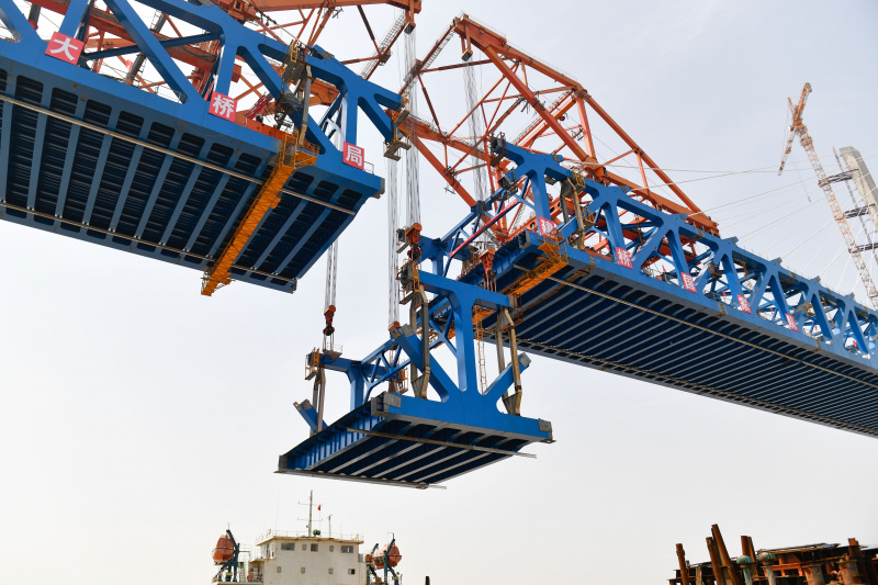 Le dernier élément en acier du tablier est hissé sur le chantier de construction du grand pont de Jiaojiang