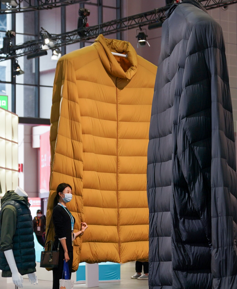Des manteaux géants présentés sur le stand de la marque de vêtements de loisirs Uniqlo attirent les visiteurs dans la zone d'exposition des biens de consommation lors de la 3e édition de l'Exposition internationale d'importation de la Chine (CIIE) à Shanghai