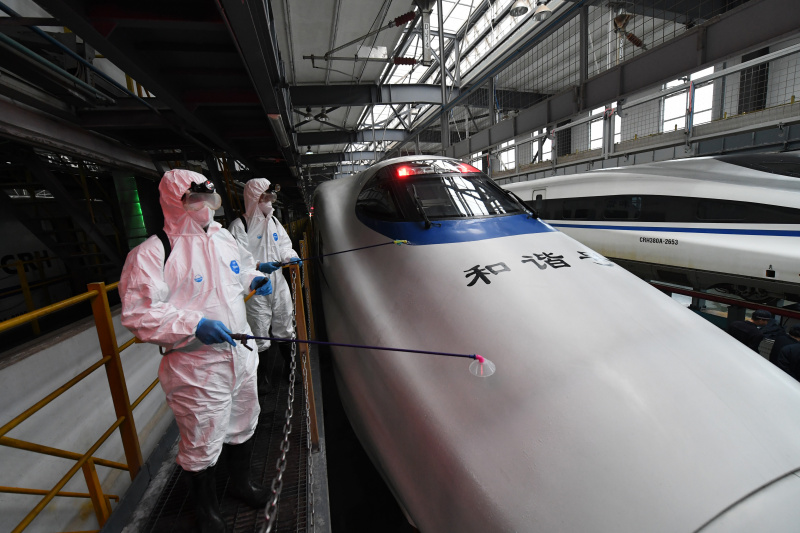 Des membres du personnel désinfectent un train à grande vitesse dans une base d'entretien à Nanning
