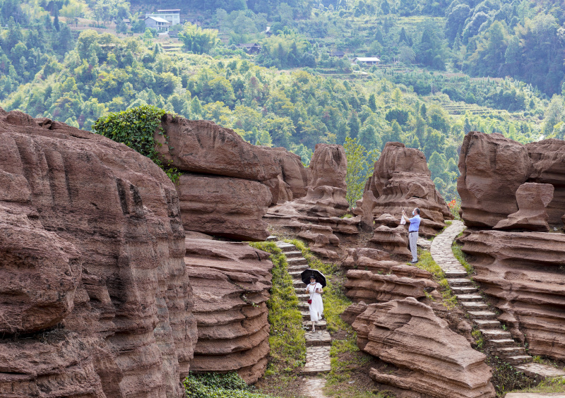 Des touristes visitent un géoparc forestier de roches rouges dans le district autonome Tujia et Miao de Youyang