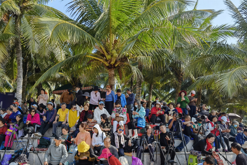 Des touristes attendent le lancement d'une fusée sur la plage de la baie Qishui