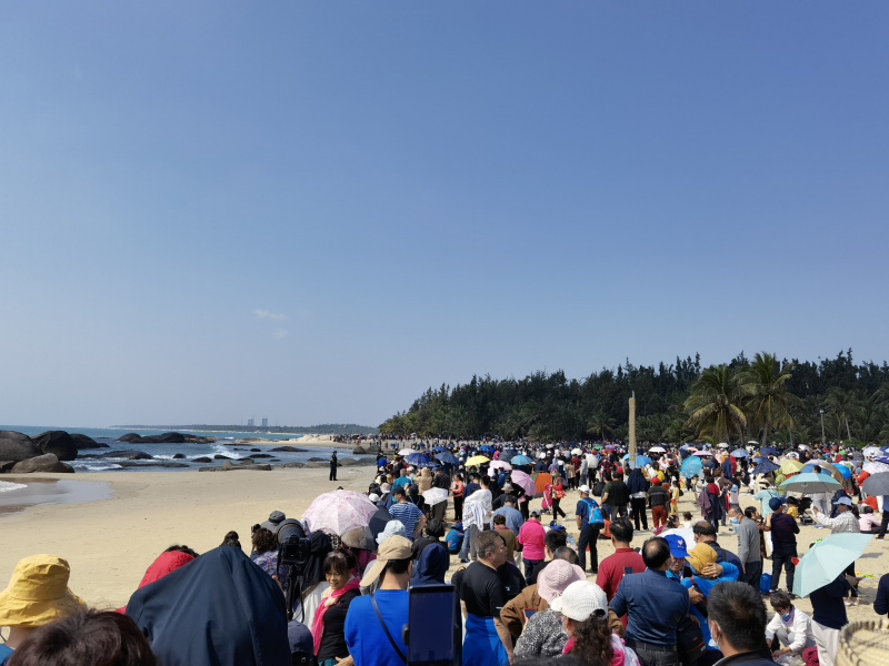 Des touristes attendent le lancement d'une fusée sur la plage de la baie Qishui