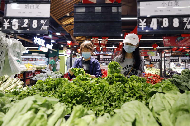 Des habitants achètent des légumes dans un marché respectant les mesures de prévention et de contrôle de la COVID-19 à Chengdu