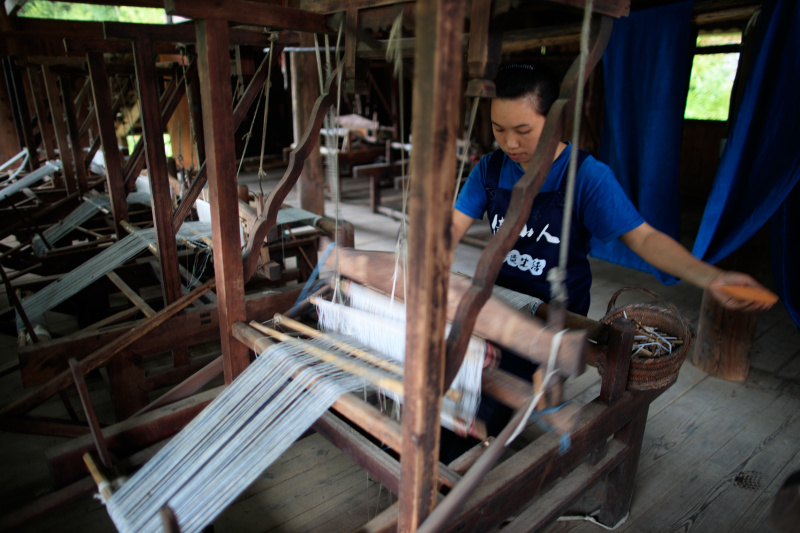 Une femme tisse des étoffes dans un atelier du village Dong de Fengdeng