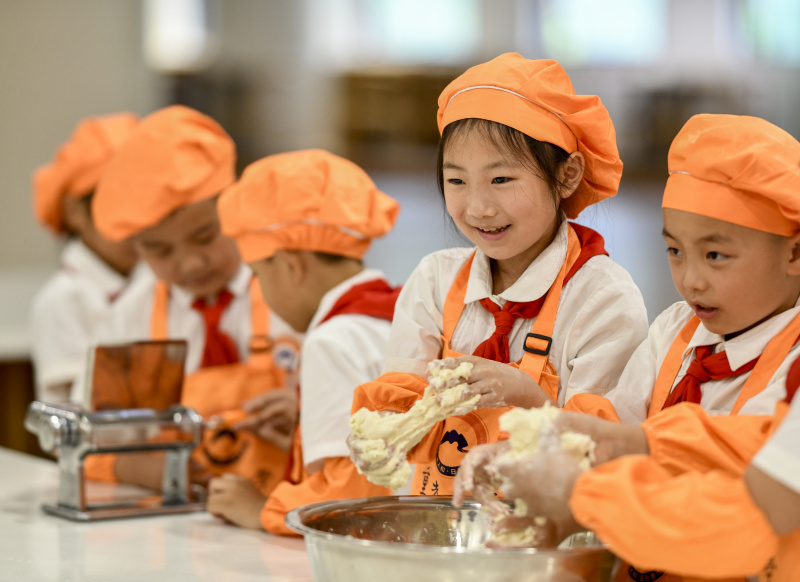 Des élèves apprennent à faire des nouilles en classe à l'école primaire de Chongguang à Chongqing