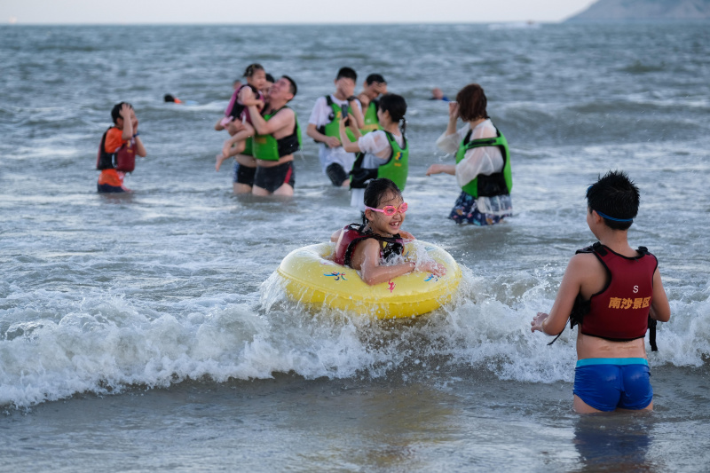 Des touristes portant des gilets de sauvetage gratuits sur la plage de Nansha